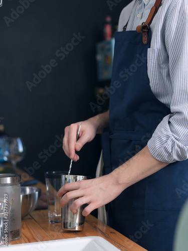 A man cook in a blue apron is cooking in the kitchen, the process of preparing a cocktail