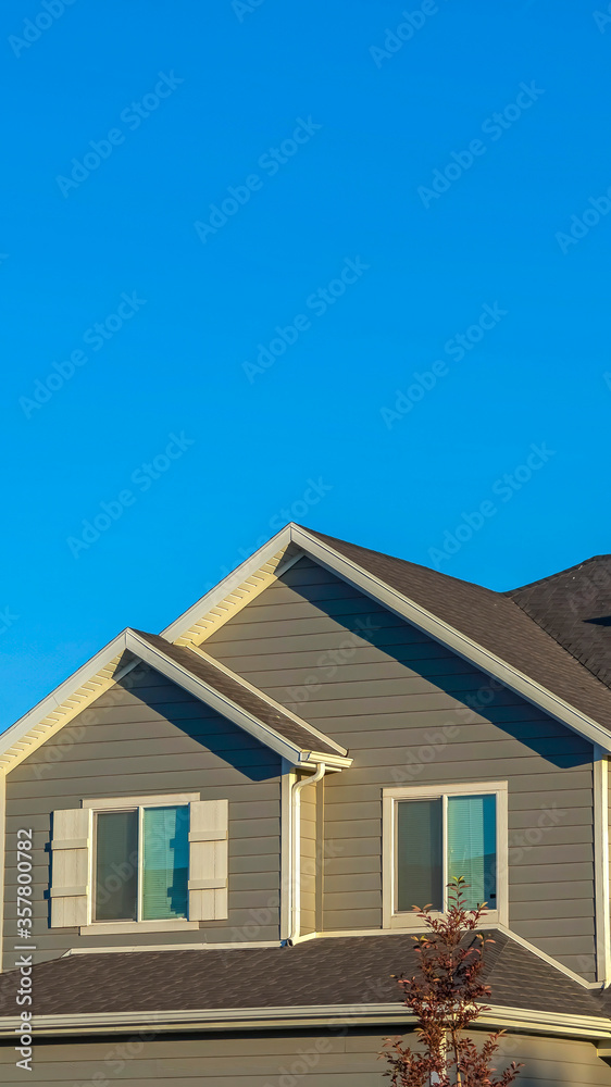 Vertical frame Home exterior with view of the upper storey agaist clear blue sky background Vertical frame Home exterior with view of the upper storey agaist clear blue sky background
