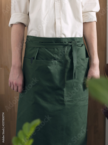Man cook in a green apron and white shirt on a wooden background