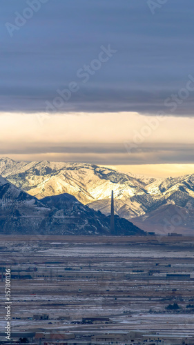 Vertical Sweeping view of Salt Lake City bordered by towering sunlit snowy mountain