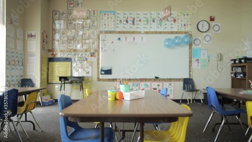 Empty elementary school classroom with white board, table and chairs, slider shot.