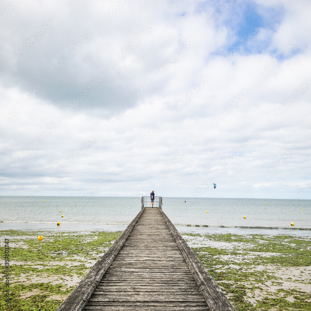 wooden pier on the beach with a man standing and algae wooden pier on the beach with a man standing and algae