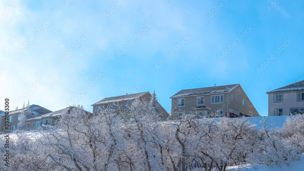 Panorama Blue sky and bright sun over homes on snow covered Wasatch Mountain in winter