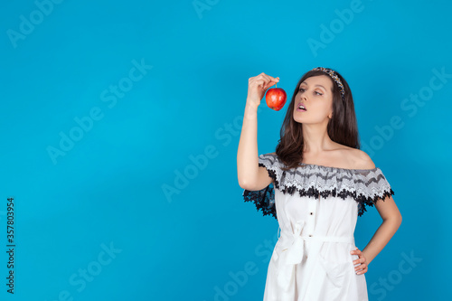  Young beautiful girl with dark hair, bare shoulders and neck, holding big red apple to enjoy the taste and are dieting, healthy eating and organic foods, feeling temptation, smile. Isolate 