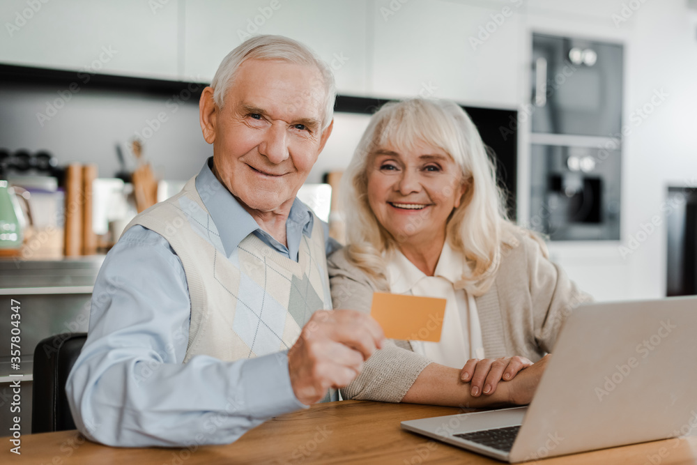 happy senior couple shopping online with credit card and laptop at home during quarantine happy senior couple shopping online with credit card and laptop at home during quarantine
