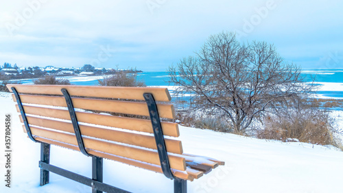 Panorama frame Magnificent scenery at the Utah Lake with an empty bench on the snowy terrain