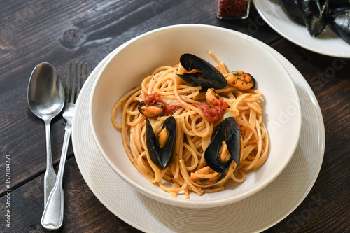 Seafood pasta spaghetti with mussels in tomato sauce on wooden table. seafood recipe. selective focus top view.  restaurant  food delivery