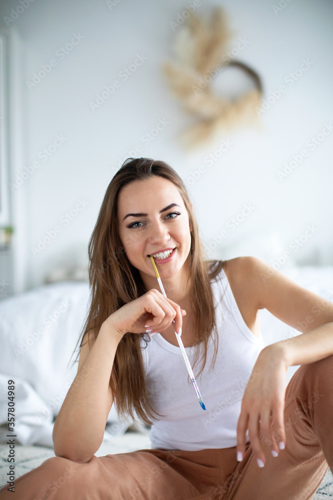 Portrait of a young beautiful female artist or designer with art brush in hand. Work at home. Portrait of a young beautiful female artist or designer with art brush in hand. Work at home.