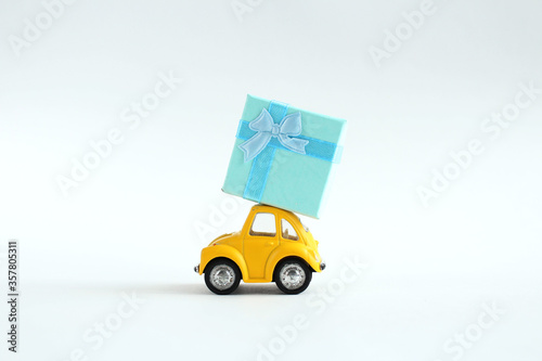 Yellow toy car delivering gift box