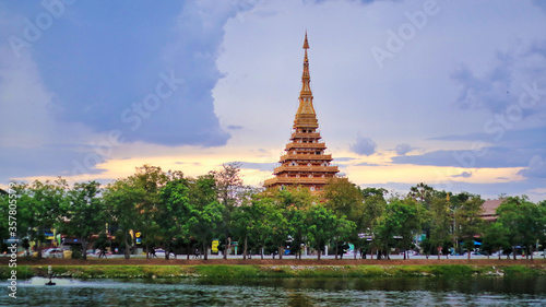 Tableau sur toile Beautiful sunset view of golden nine storey Called Phra Mahathat Kaen Nakhon or Wat Nong Wang surrounded with lake at Khon Kaen town