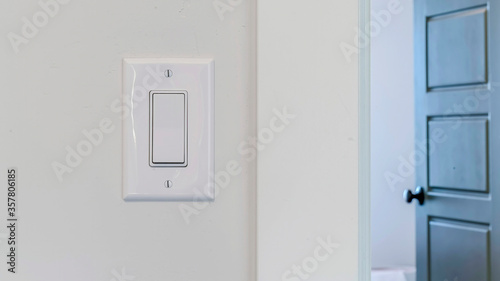 Panorama frame Electrical rocker light switch on white wall against blurry door background