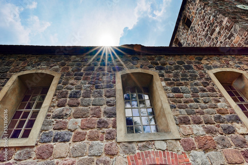 Details of a historic medieval church in Berlin, Germany. You can see the nave and the tower. Sunbeams can be seen above the roof.