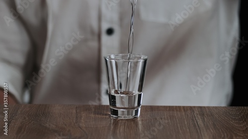 The bartender pours sambuca from jigger to cocktail glass photo