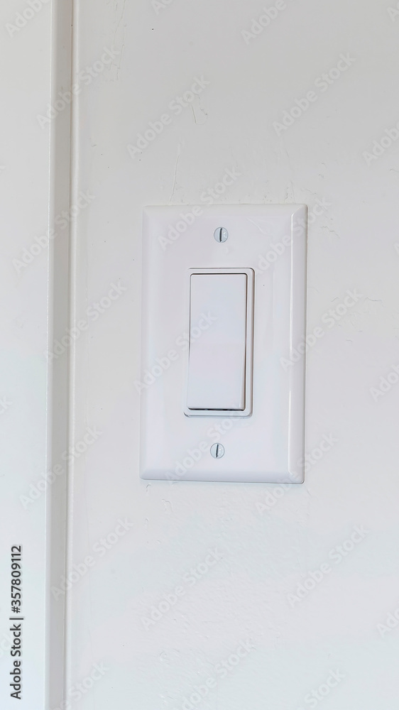 Vertical Indoor electrical light switch of home mounted on white wall background Vertical Indoor electrical light switch of home mounted on white wall background