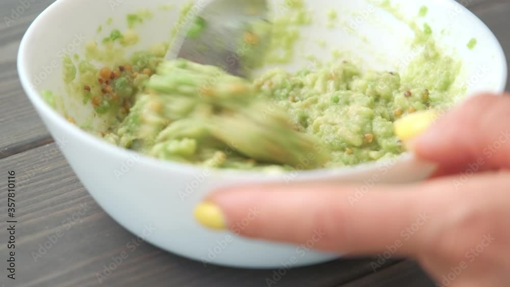 Hands mashing avocado in bowl with a fork. Table top view footage. Healthy food cooking Hands mashing avocado in bowl with a fork. Table top view footage. Healthy food cooking