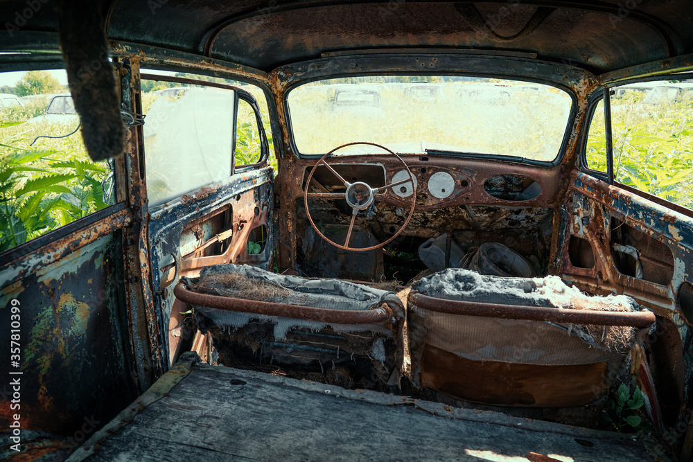 Inside interior of Old retro rusty abandoned car overgrown with grass, close up.