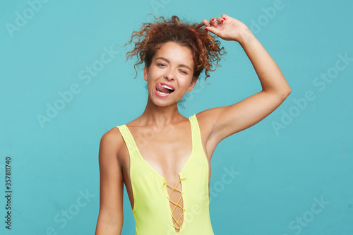 Quadro su tela Indoor photo of young joyful curly female with casual hairstyle sticking out her