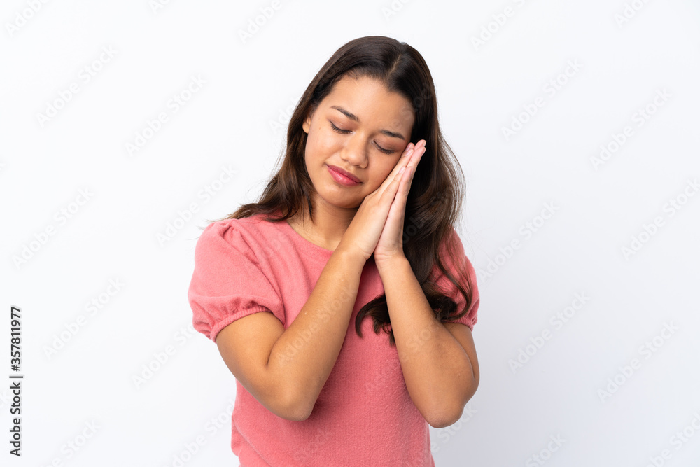 Young Colombian girl over isolated white background making sleep gesture in dorable expression Young Colombian girl over isolated white background making sleep gesture in dorable expression