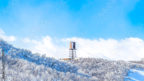 Panorama Wasatch Mountains landscape with water tank tower on the snowy slope in winter