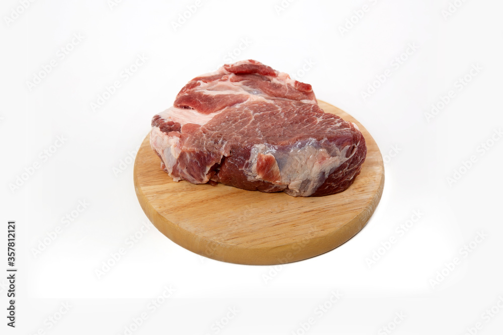 a piece of raw meat pork on a wooden backing