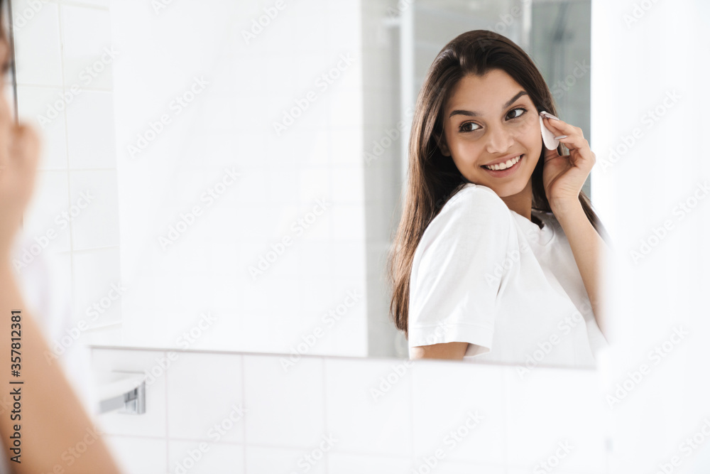 Photo of happy nice woman smiling and cleaning face with cotton pad Photo of happy nice woman smiling and cleaning face with cotton pad