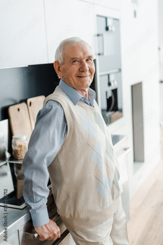 Fototapeta premium smiling elderly man on kitchen during quarantine