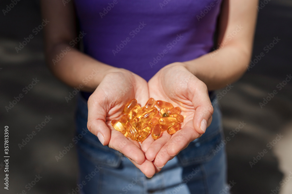 A handful of vitamin d capsules are in women's hands. Blurred background A handful of vitamin d capsules are in women's hands. Blurred background