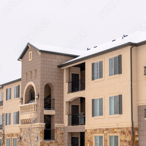 Square Facade of an apartment building against cloudy sky and snowy ground in winter