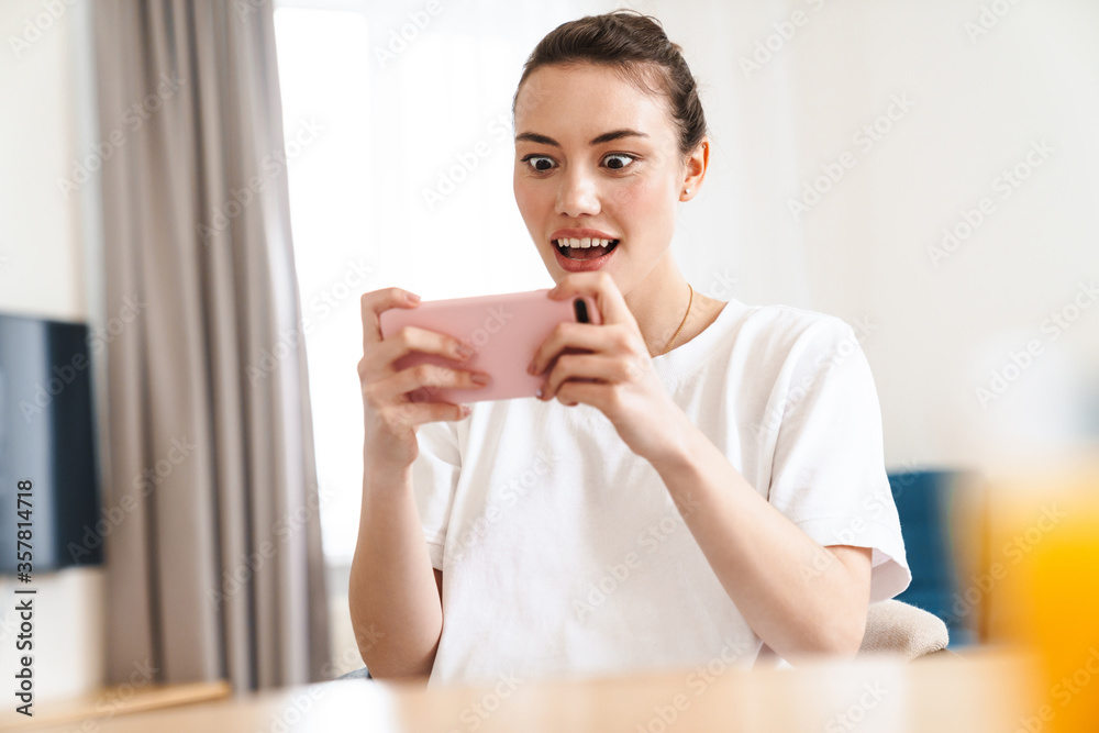 Photo of delighted woman playing video game on mobile Photo of delighted woman playing video game on mobile