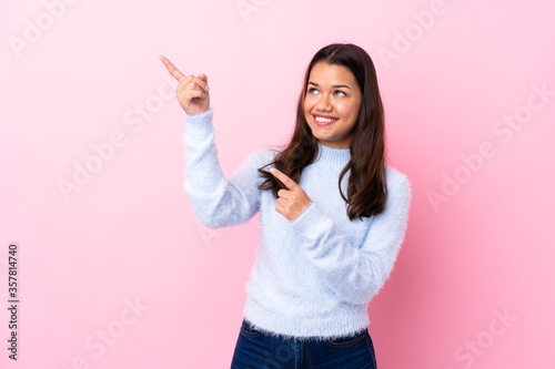 Young Colombian girl over isolated pink background pointing with the index finger a great idea © luismolinero