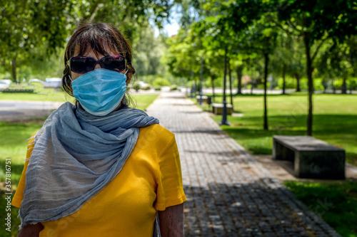 Woman wearing face mask in public park; selective focus.