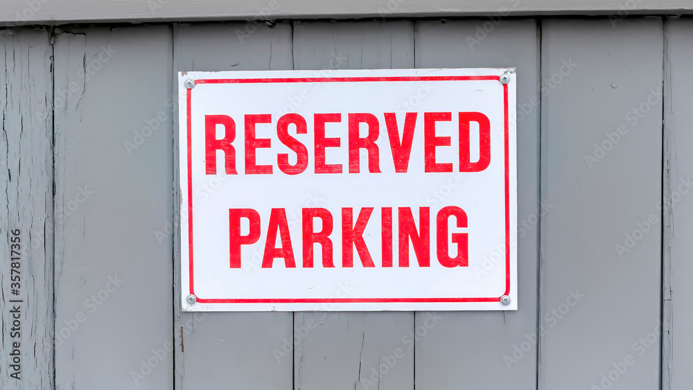 Panorama Reserved Parking sign board on a gray wooden wall topped with snow in winter