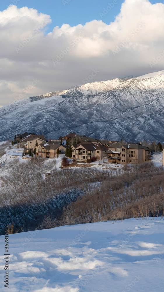 Vertical crop Pristine landscape of Wasatch Mountains with houses on its snow covered terrain