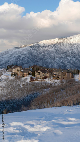 Vertical crop Pristine landscape of Wasatch Mountains with houses on its snow covered terrain