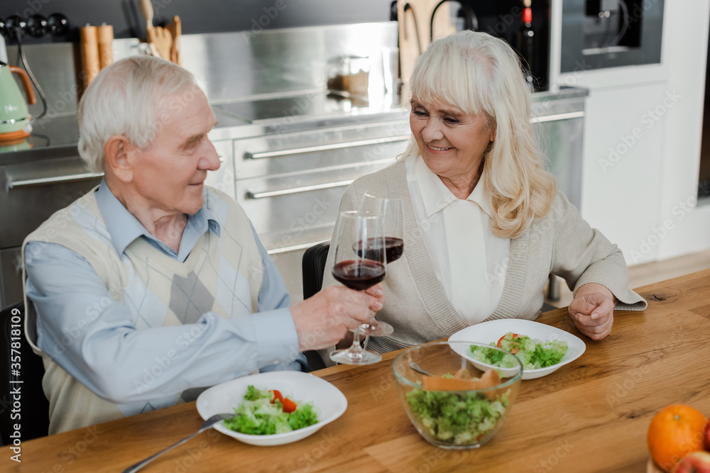 happy senior husband and wife having dinner with wine and salad at home on self isolation happy senior husband and wife having dinner with wine and salad at home on self isolation
