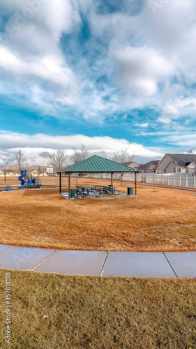 Vertical crop Neighborhood landscape with recreational park and homes under blue cloudy sky