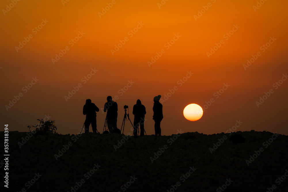 Silhouette of a group of photographers taking a sunrise picture from a mountain in Bahrain
