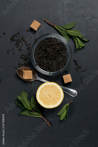 Tea in glass bowl with mint leaves and lemon on a dark background. Top view. Copy space
