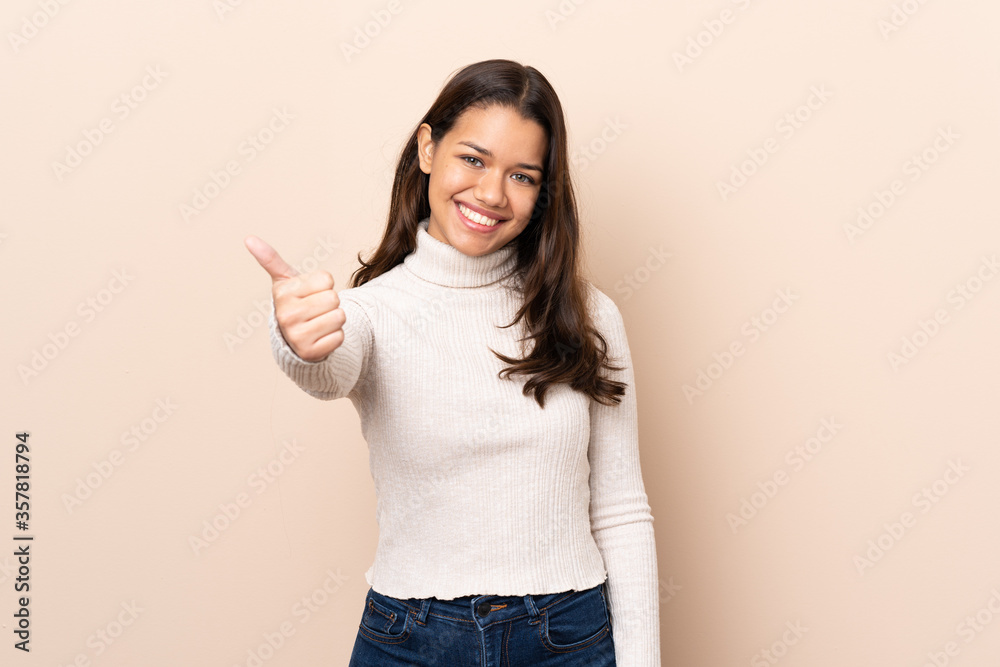 Young Colombian girl over isolated background with thumbs up because something good has happened Young Colombian girl over isolated background with thumbs up because something good has happened