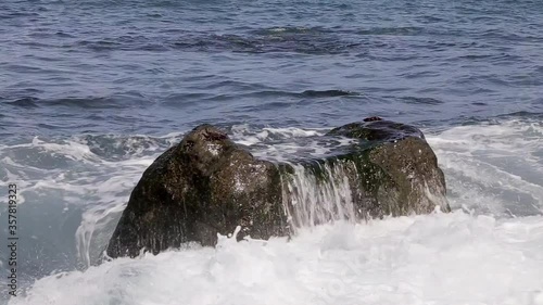 A large stone is washed in full by the big waves. The sound of seawater waves.