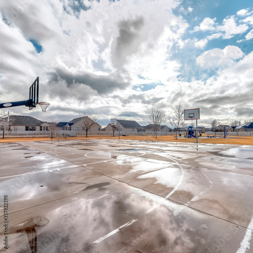 Square crop Basketball courts with neighborhood houses background under blue sky and clouds