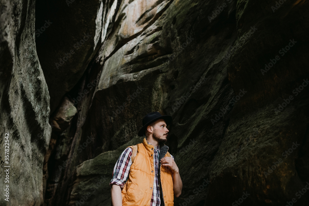 Lifestyle Portrait of a hipster traveler in a hat and with a backpack in a mountain cave Lifestyle Portrait of a hipster traveler in a hat and with a backpack in a mountain cave