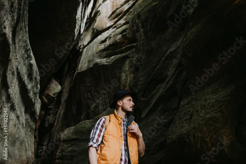 Lifestyle Portrait of a hipster traveler in a hat and with a backpack in a mountain cave