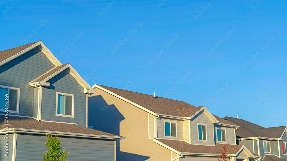 Panorama frame Homes with horizontal wall sidings and front gable roofs againts clear blue sky Panorama frame Homes with horizontal wall sidings and front gable roofs againts clear blue sky