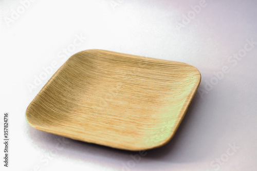 Square Areca Leaf Plate, eco-friendly disposable cutlery. Side view on a white background.