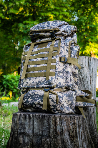 Foto New camouflage backpack for hiking and traveling on old tree stump in summer for