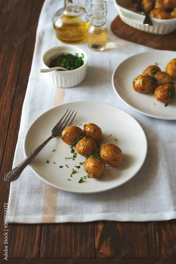 Oven-baked potatoes with garlic and herbs on plate. Summer food eating. Oven-baked potatoes with garlic and herbs on plate. Summer food eating.