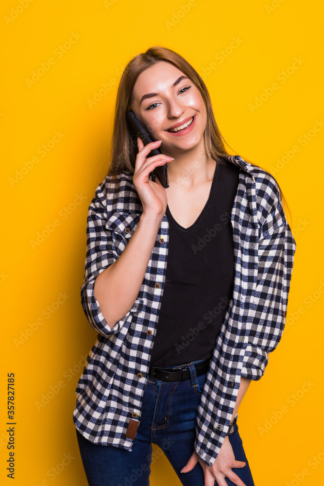 Young woman talking on phone against yellow background Young woman talking on phone against yellow background
