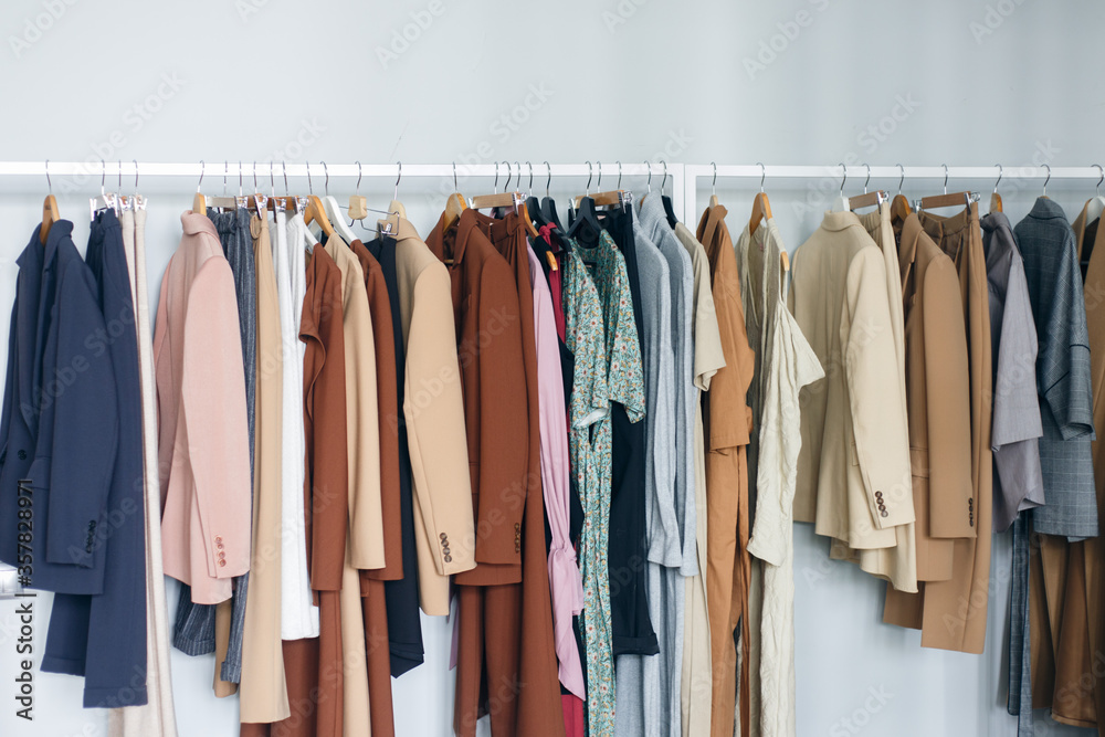 Clothes hanging on rail in modern closet or in a small shop, showroom. Colors of fall and summer. Clothes hanging on rail in modern closet or in a small shop, showroom. Colors of fall and summer.