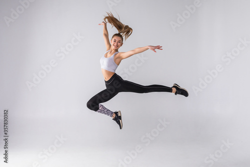 Fototapeta Naklejka Na Ścianę i Meble -  Happy young fitness woman jumping over white background